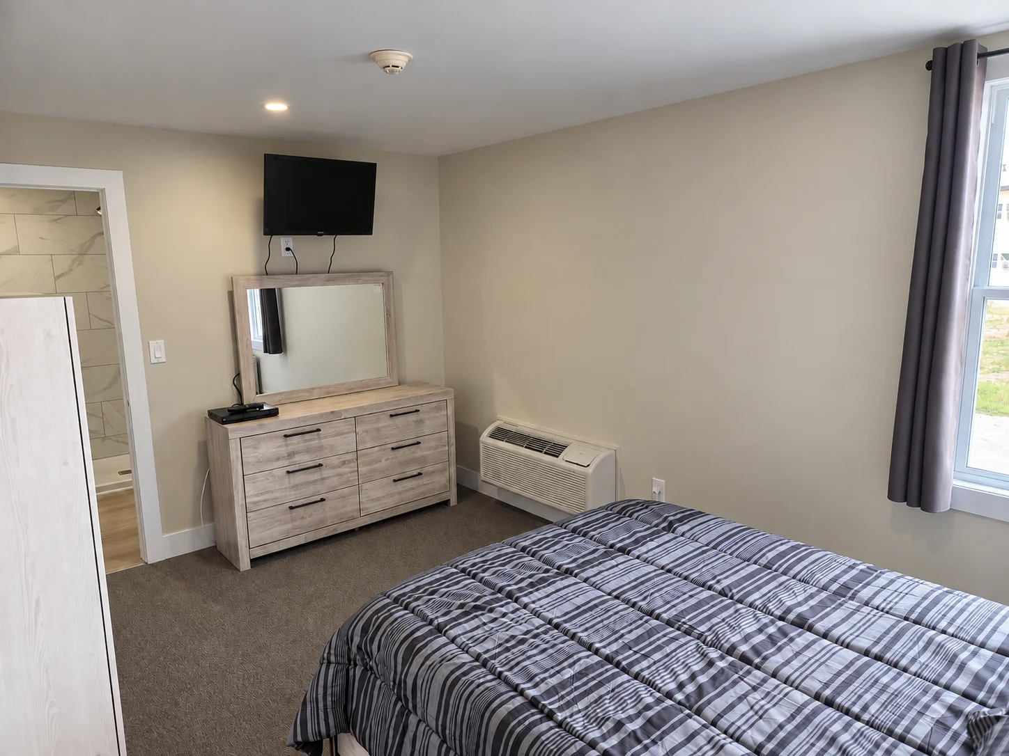Guest room with TV, dresser and private bathroom entrance